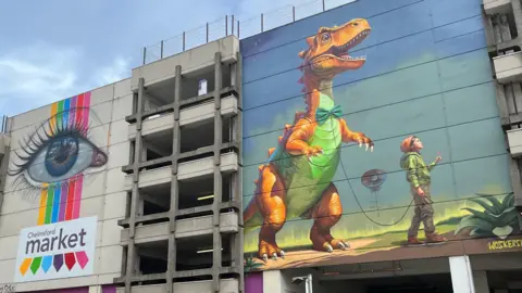 Stuart Woodward/BBC A dinosaur mural painted on the side of Chelmsford Market car park.