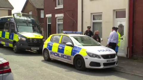 Police car and officers outside a house where a raid had taken place in connection with terror offences