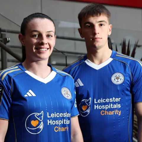 LCFC/Plumb Images Two players wearing the blue home kits of Leicester City with a Leicester Hospitals Charity logo front and centre