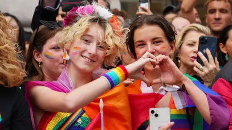 Two people make a loveheart symbol at a London Pride march