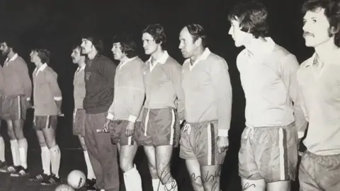 Workington AFC A black and white image of players lined up on a pitch in their football kit, including Bobby Charlton.