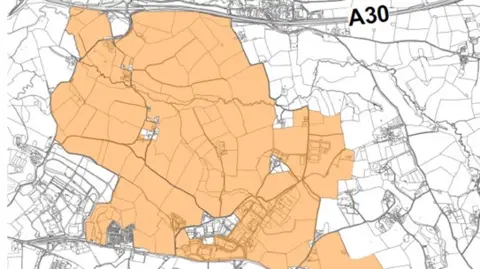 A black and white map of land to the south of Exeter Airport, with a proposed development area highlighted in colour