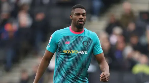 A photo of Emile Acquah, wearing a light blue Harrogate Town kit, during the side's game against MK Dons in March