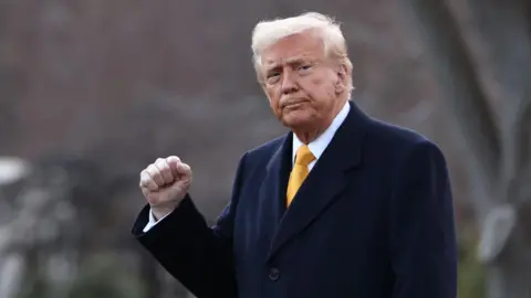 Reuters U.S. President Donald Trump, dressed in a yellow tie and navy coat, raises a fist as he walks to board Marine One