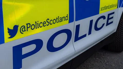 The side of a police car with Police and Police Scotland written on it