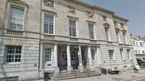 Google Outside Lewes Crown Court, a large, grey stone building with four large pillars and stone steps at the entrance