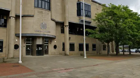 Google The exterior of Bradford Crown Court, a beige brick building with silver revolving doors.