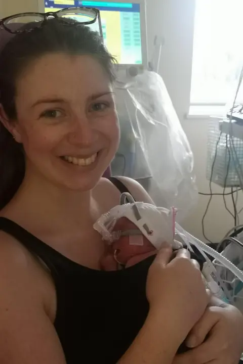 Hayley Steel A mother holds her newborn daughter on her chest - the baby is premature and has tubes coming out of her.