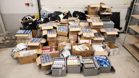 A large number of boxes of cigarettes stacked on top of each other on the floor of a property.