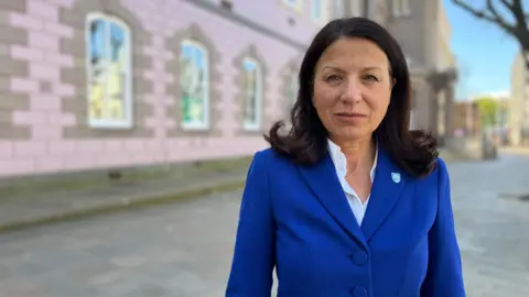 Woman wearing blue blazer in front of States building 