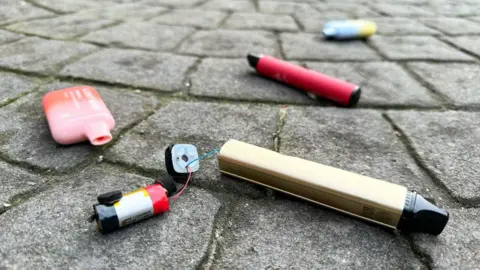 Getty Images A file image showing a number of discarded disposable vapes in the ground of a carpark in London, including a gold-coloured vape which has split open at the bottom to reveal a battery inside that is wired up to the vape casing