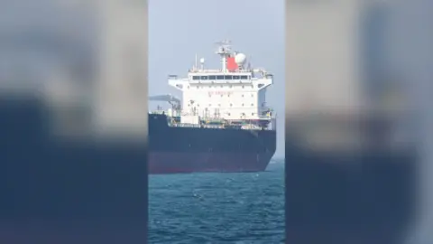 A large white, black and red cargo ship on a body of water