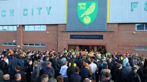 Getty Images A crowd of around 50 football fans are stood outside the doors to a stadium, with a sign above describing it as the directors' entrance.