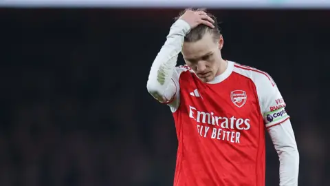 Arsenal captain Martin Odegaard runs his hand through his hair and looks disappointed