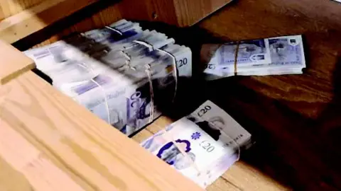 SWROCU Bundles of £20 notes bound with elastic bands in a wooden box