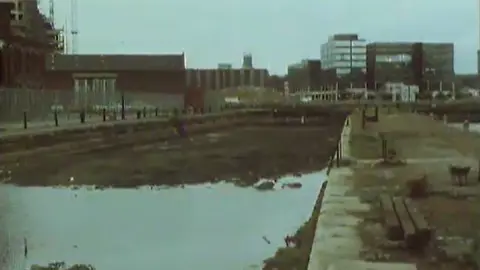 BBC Archives Disused dockland with empty basin and rubble.