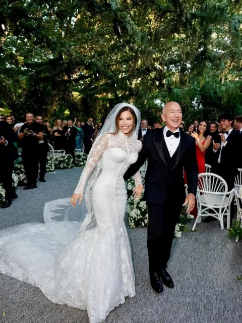 Instagram/Reuters Lauren Sánchez wears a Dolce & Gabbana haute couture gown while Jeff Bezos places his arm around her while wearing a smart black tuxedo 