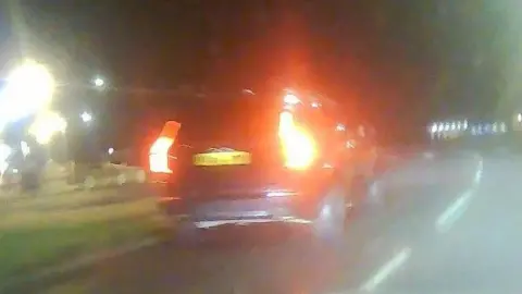 Northumbria Police Still from dashcam showing a large black SUV type vehicle approaching a roundabout at night.
