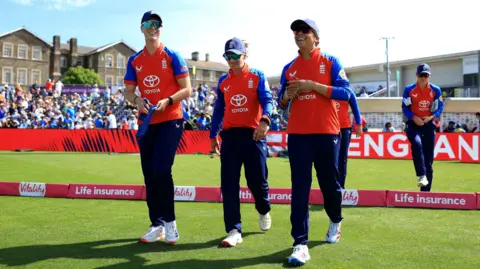 Getty Images Five England women cricketers, in their red and blue one-day international kit, walk over the boundary onto the pitch ahead of their international against India in Bristol