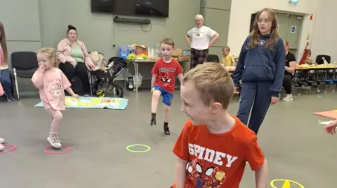 Helen Boyle children dancing and laughing in a large room. 