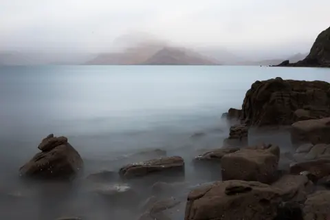 Michael G. O’Callaghan Landscape image using slow shutter speed of a blurry loch with fog covered hills in the distance