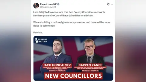 x.com/RupertLowe10 Facebook post showing a photo of two men wearing suits and ties with the union jack in the background. The man on the left wears a blue suit and white shirt. The man on the right wears a black shirt and tie and grey shirt.