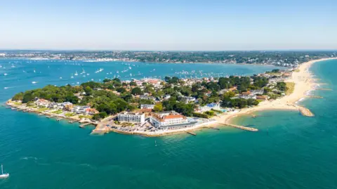 Getty Images An aerial shot of Sandbanks, a built-up piece of land in the sea. Several groynes made from large rocks can be seen protruding from the beaches into the sea.