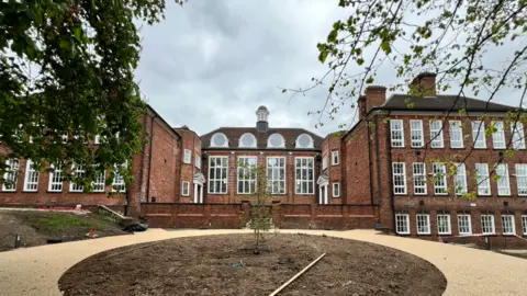 Amber Valley Borough Council Large orange brick building with large rectangular white framed windows offset by courtyard
