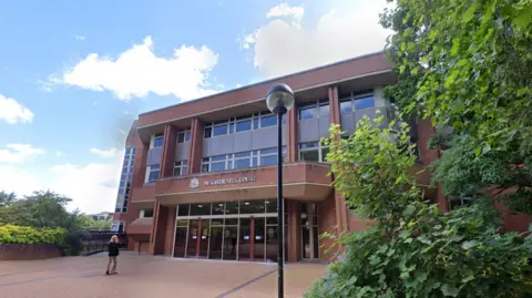 Google Coventry Magistrates Court, a brick building which lots of front-facing windows surrounded by bushes