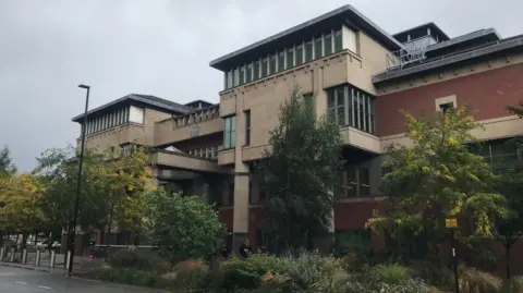 Exterior of modern red-brick and brown court building, with columns on its facade.