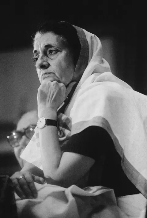 Raghu Rai / The India Today Group via Getty Images A profile shot of former India PM Indira Gandhi, wearing a saree, attentively listens with her fist on her chin, at an All India Congress Committee meeting in Delhi.