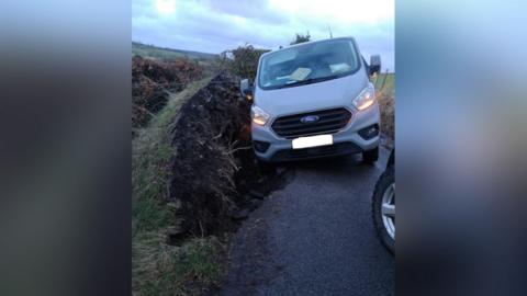 Van stuck in a hole in road