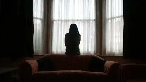 A woman in a darkened room. 