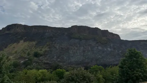 Arthur's Seat with burnt vegetation down its cliff face.
