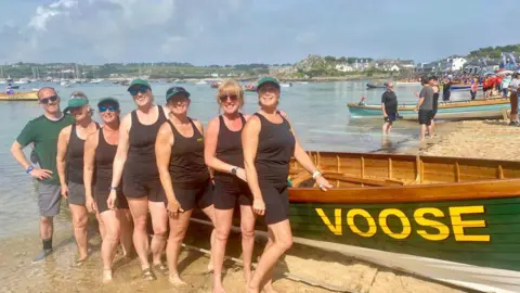 Helford Women's SV Winners Cox - Gary Jago 6 - Becks Campbel 5 - Dee Williams 4 - Mel Williams 3 - Hattie Walker 2 - Catherine Nancarrow 1 - Sue Gibson stood beside a green boat. 