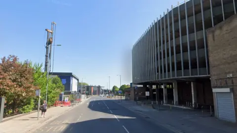 George Street in Hull. A large multi-storey car park is on the right. The sky is blue.
