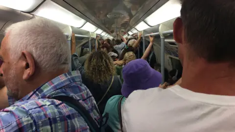 Tube train full of passengers holding the rails