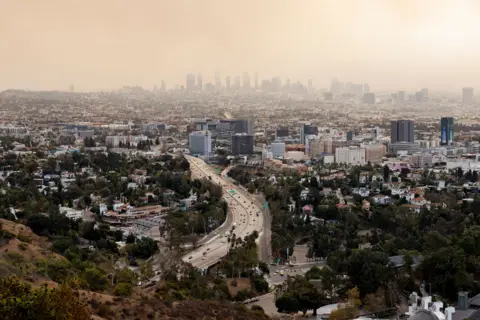 Carlin Stiehl/Reuters Asap tebal memenuhi cakrawala LA saat beberapa kebakaran terjadi di Los Angeles pada hari Rabu.