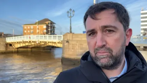 Andrew Turner/BBC Richard Goffin standing next to Haven Bridge