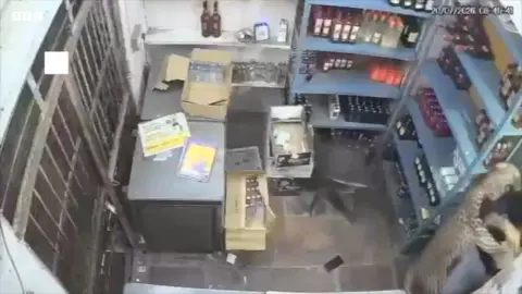 CCTV shot of a leopard jumping on a man in a shop.