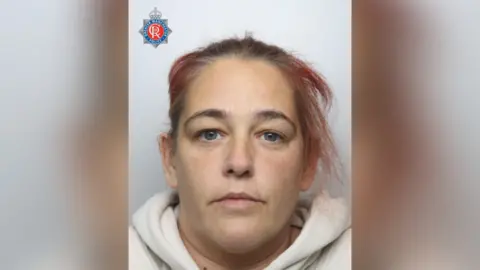 Greater Manchester Police A woman with blue eyes and red dyed hair in police mugshot.