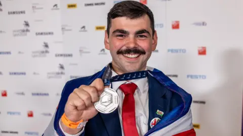 WorldSkills UK Ruben Duggan holds up his silver medal at the 'skills Olympics' in Lyon