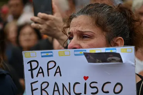 Getty Images A woman holds a sign at a mass for the healing of Pope Francis in Constitution Square, Buenos Aires, Argentina, on 24 February 2025.
