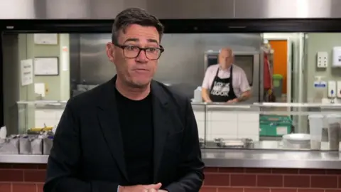 Andy Burnham wearing a black top and jacket