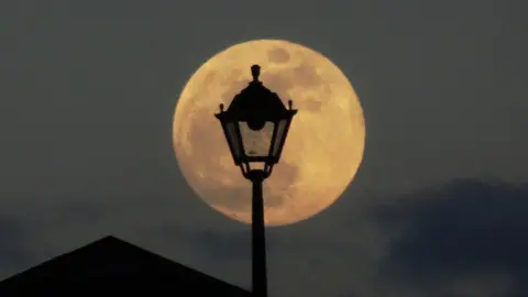 Peter and Leah/BBC Weather Watchers The Moon looks large behind a lamp post. 