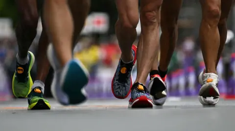 A number feet clad in trainers running down a street 