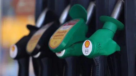 A close up of four petrol pumps in a row, two black pumps and two green ones