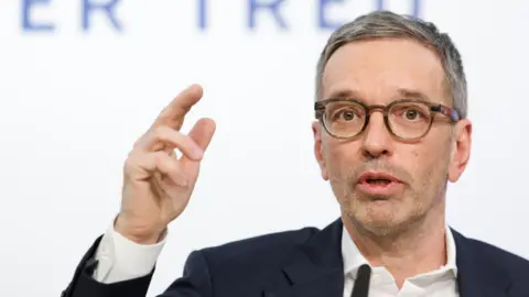 Reuters A headshot of a man with grey hair and round glasses gesturing while making a speech