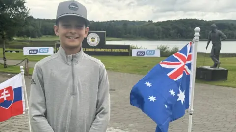 Sebastian McLeod stands beside an Australian flag