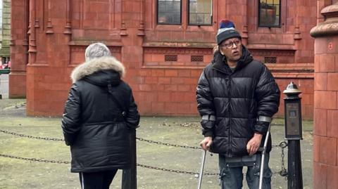 Farhat Ajaz using crutches outside Birmingham Magistrates' Court